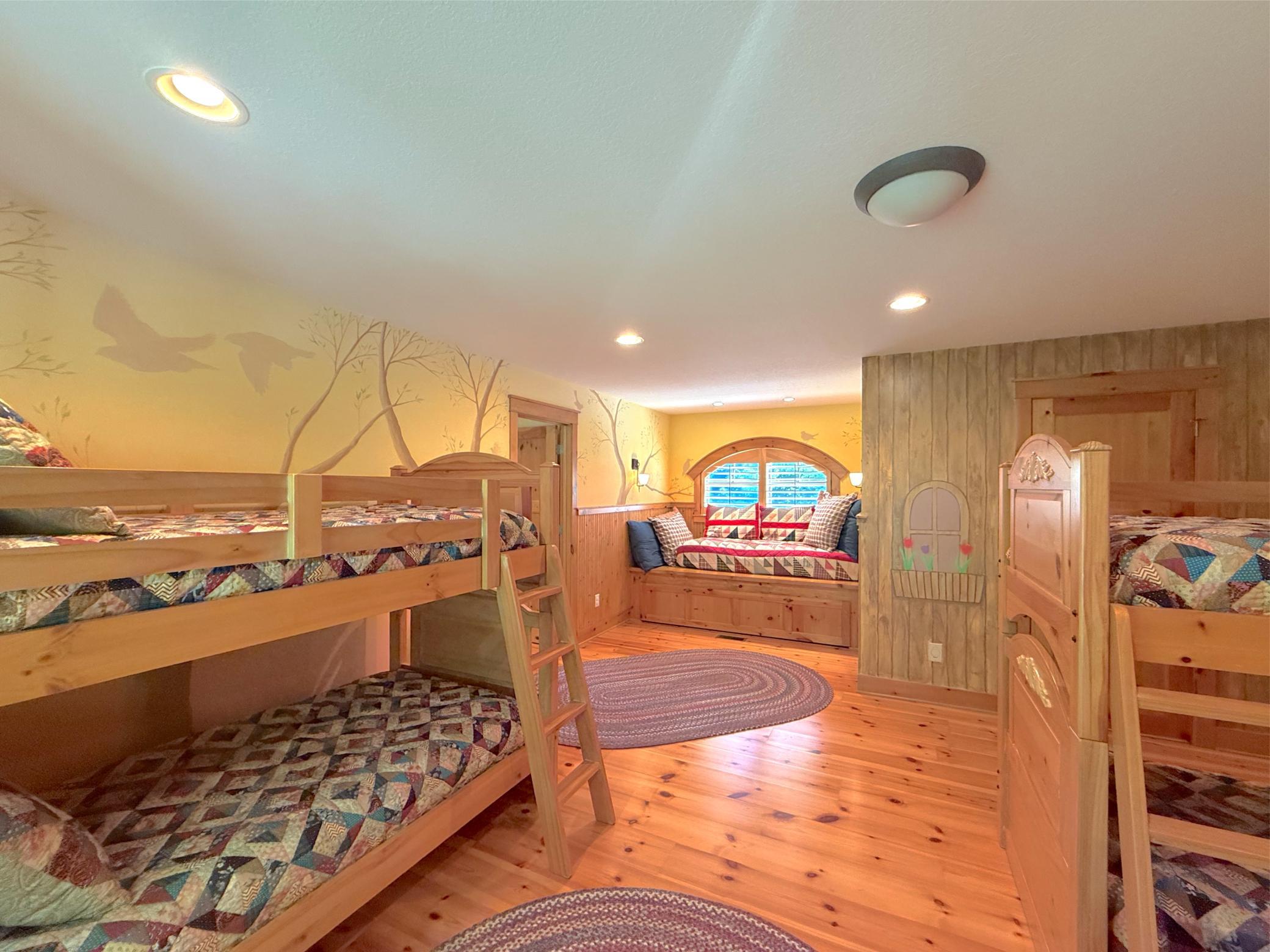 This charming bunk-room with full mural walls also includes a built-in bed with a custom pull out bed finished with a window.