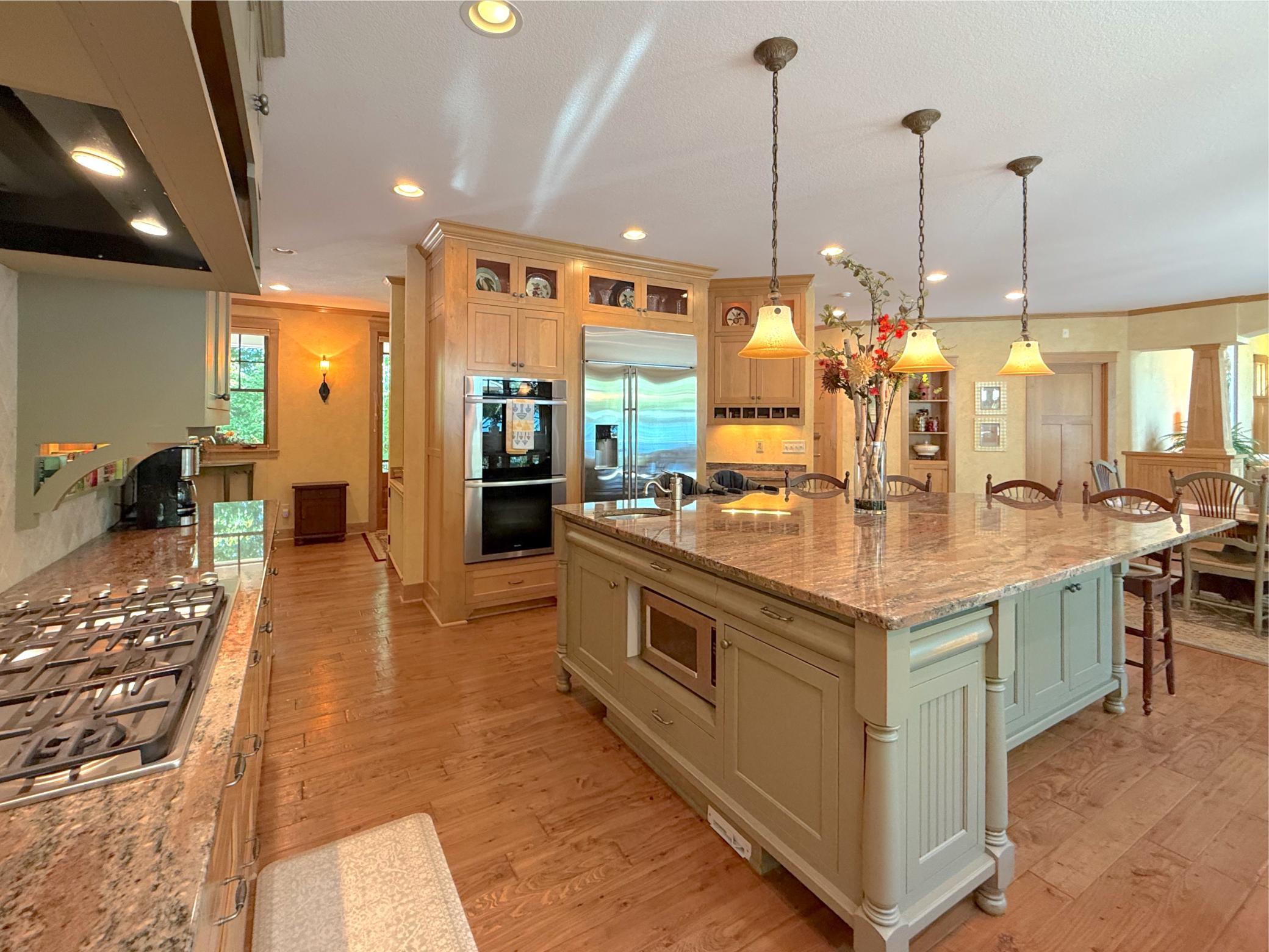Two-toned cabinets, tile backsplash and farm sink offer and country feel complete with handscraped pine floors.