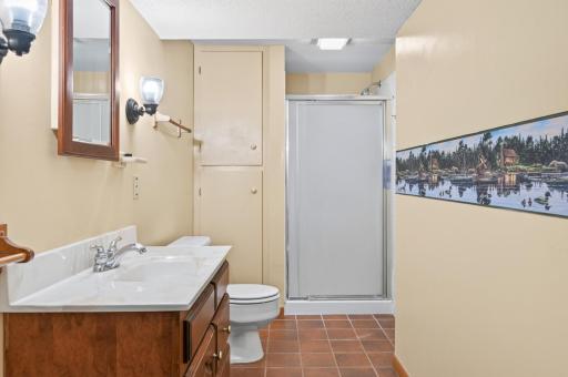 Lower level 3/4 bathroom with tiled floors and extra storage.