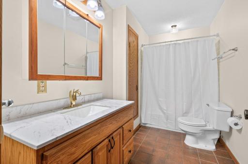 Full bathroom on the main floor features tiled flooring and extra storage.