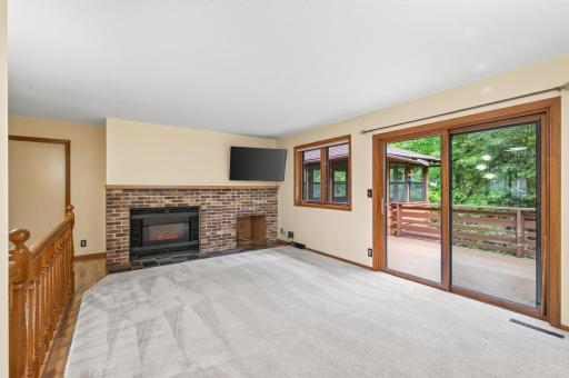 Main level living room features brick surround fireplace and sliding patio door that leads to maintenance free deck and gazebo!