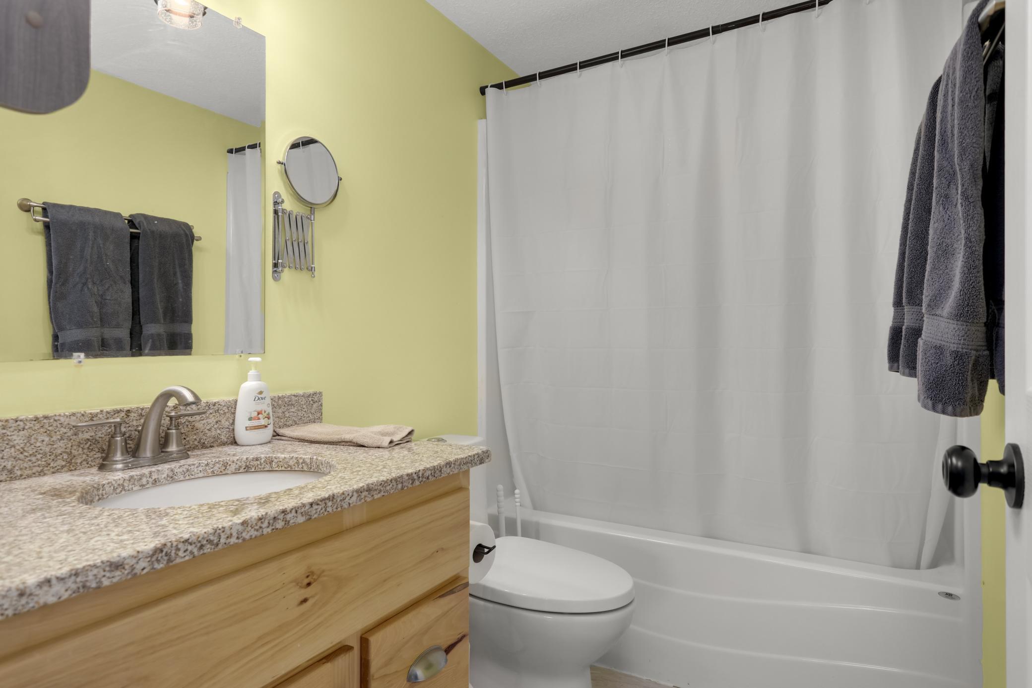 Main floor bathroom with updated vanity, stone countertops, & tile floors.