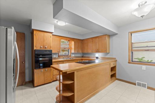 Well-kept kitchen with abundant wood cabinetry, a garden window over the sink, and a smooth cooktop with built-in wall oven — plenty of counter space to work with.