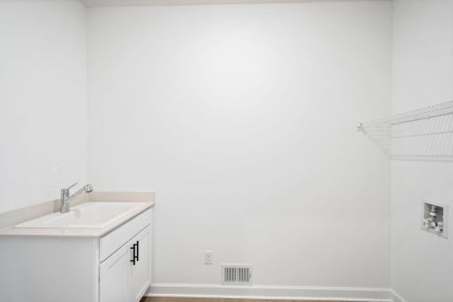 The laundry room is steps from a convenient mudroom to the side of the home. An overhead shelf and space for a new washer and dryer simplify everyday routines.