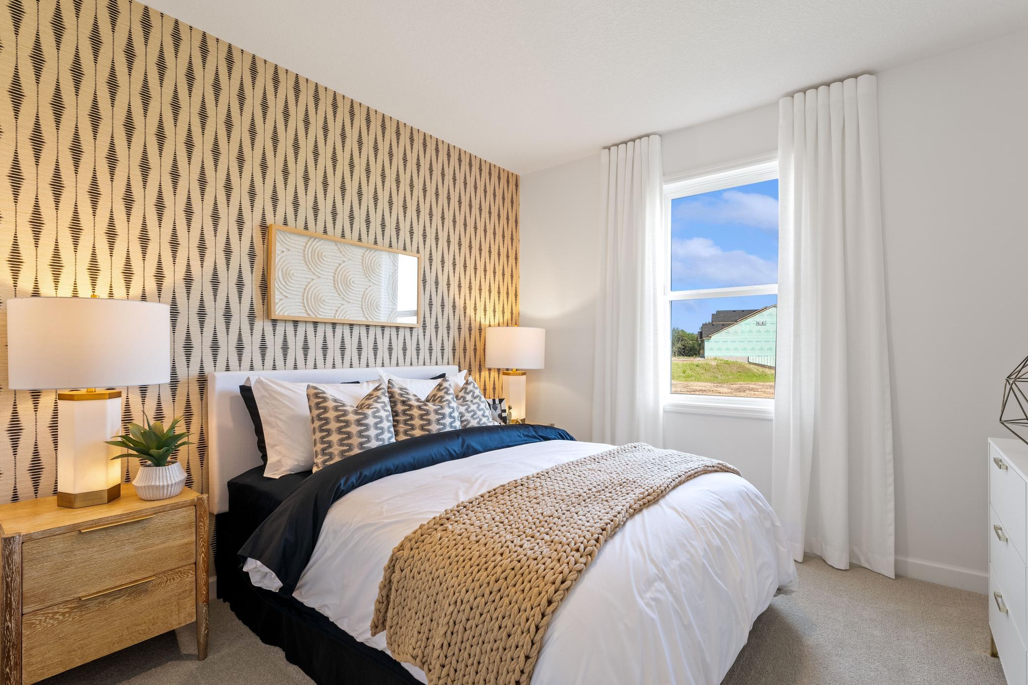 (Photo of model home, finishes will vary) This main level bedroom is sequestered from the rest of the first floor living spaces, creating a quiet environment ideal for guests.