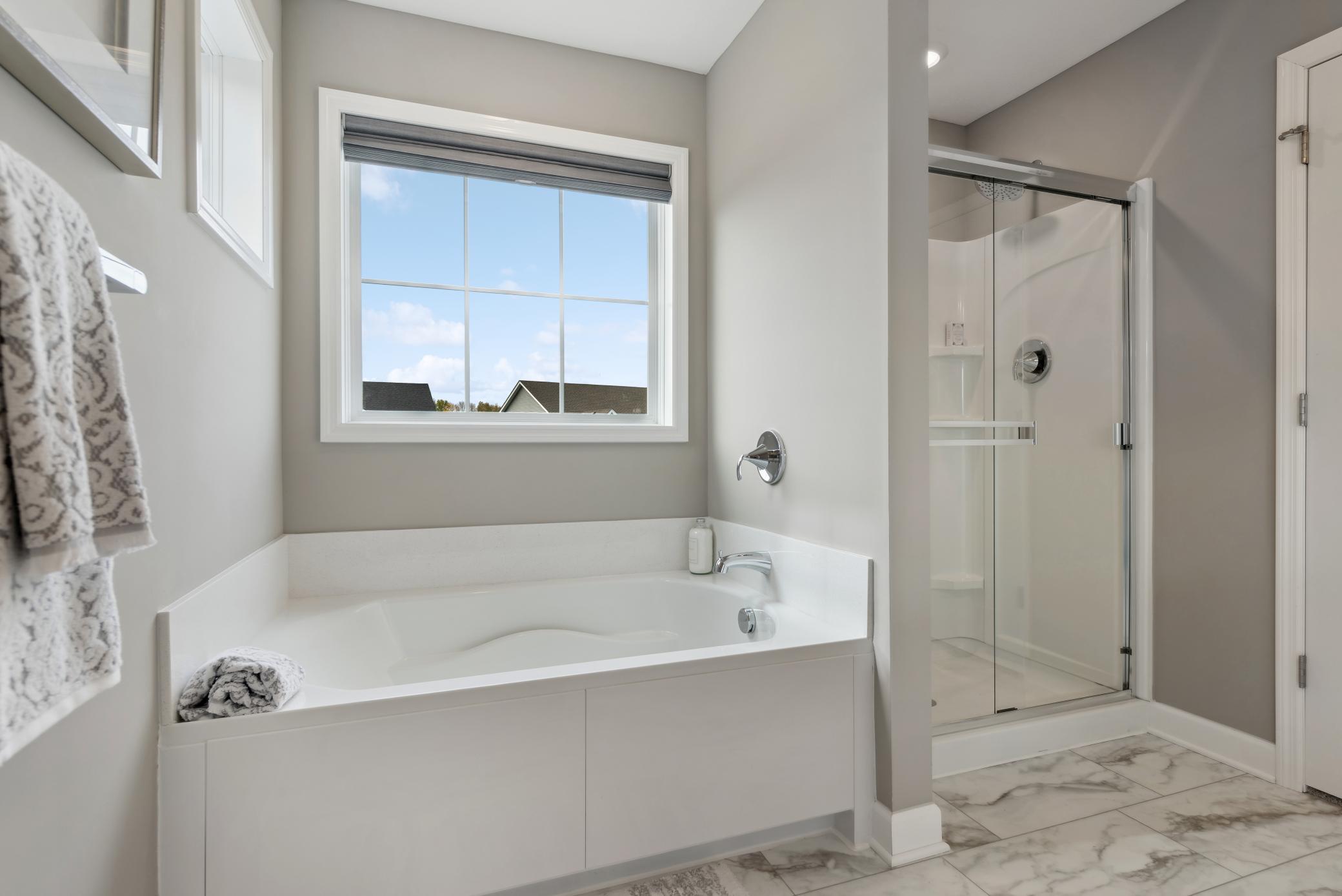 (Photo of model home, finishes will vary) A glass-enclosed shower with Sterling Vikrell surround, built-in seating and an oversized shower head are featured in the bathroom