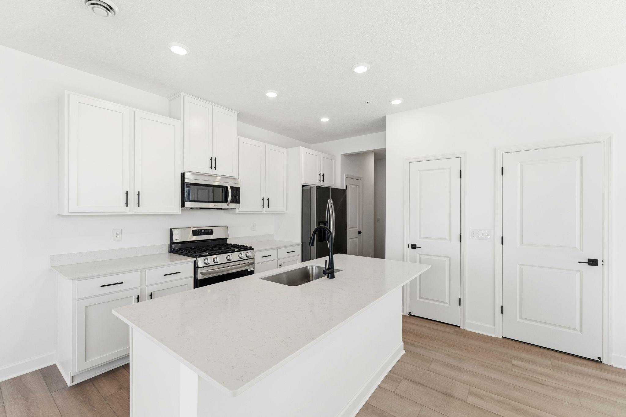 (Photo of a similar home, actual finishes may vary) This chef-ready kitchen is designed to accommodate modern living, with a multiuse center island to add food prep and seating space, gleaming quartz countertops and abundant cabinetry room.