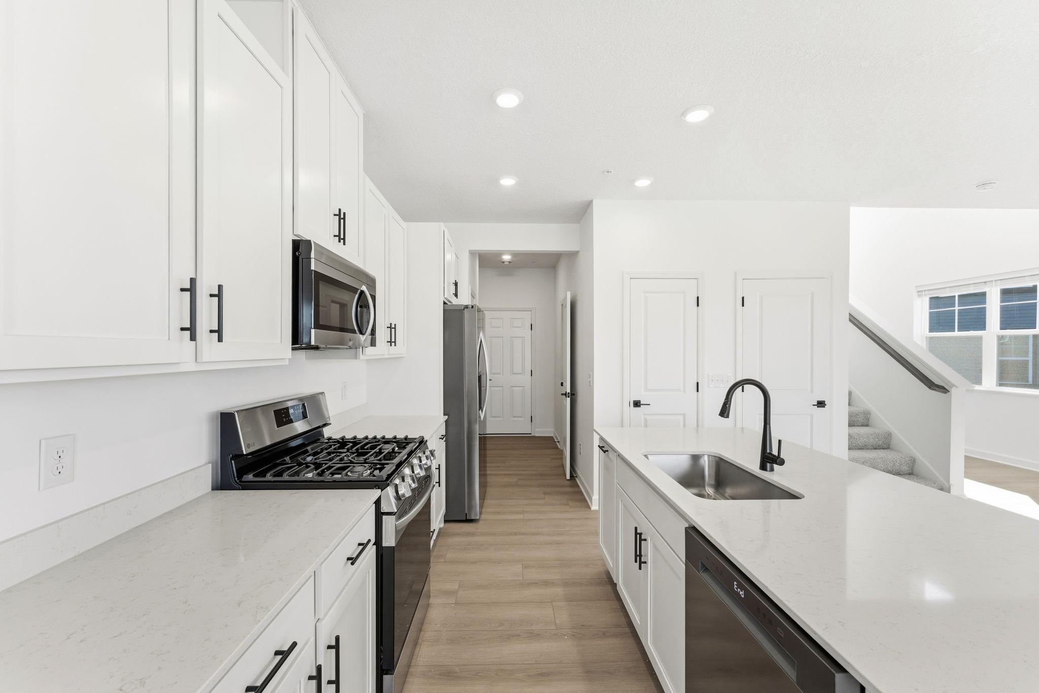 (Photo of a similar home, actual finishes may vary) A subway tile backsplash atop the 5-burner gas cooktop with an overhead microwave meets style with functionality