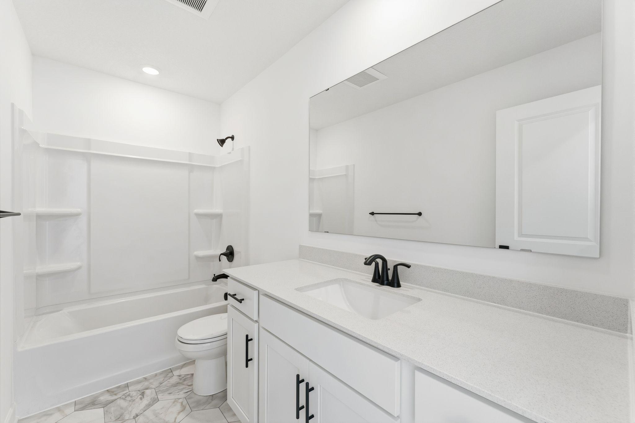 (Photo of a similar home, actual finishes may vary) A full-sized bathroom on the second floor comes well-equipped with a generously sized quartz-topped vanity and a combination shower and tub to maximize the interior space.