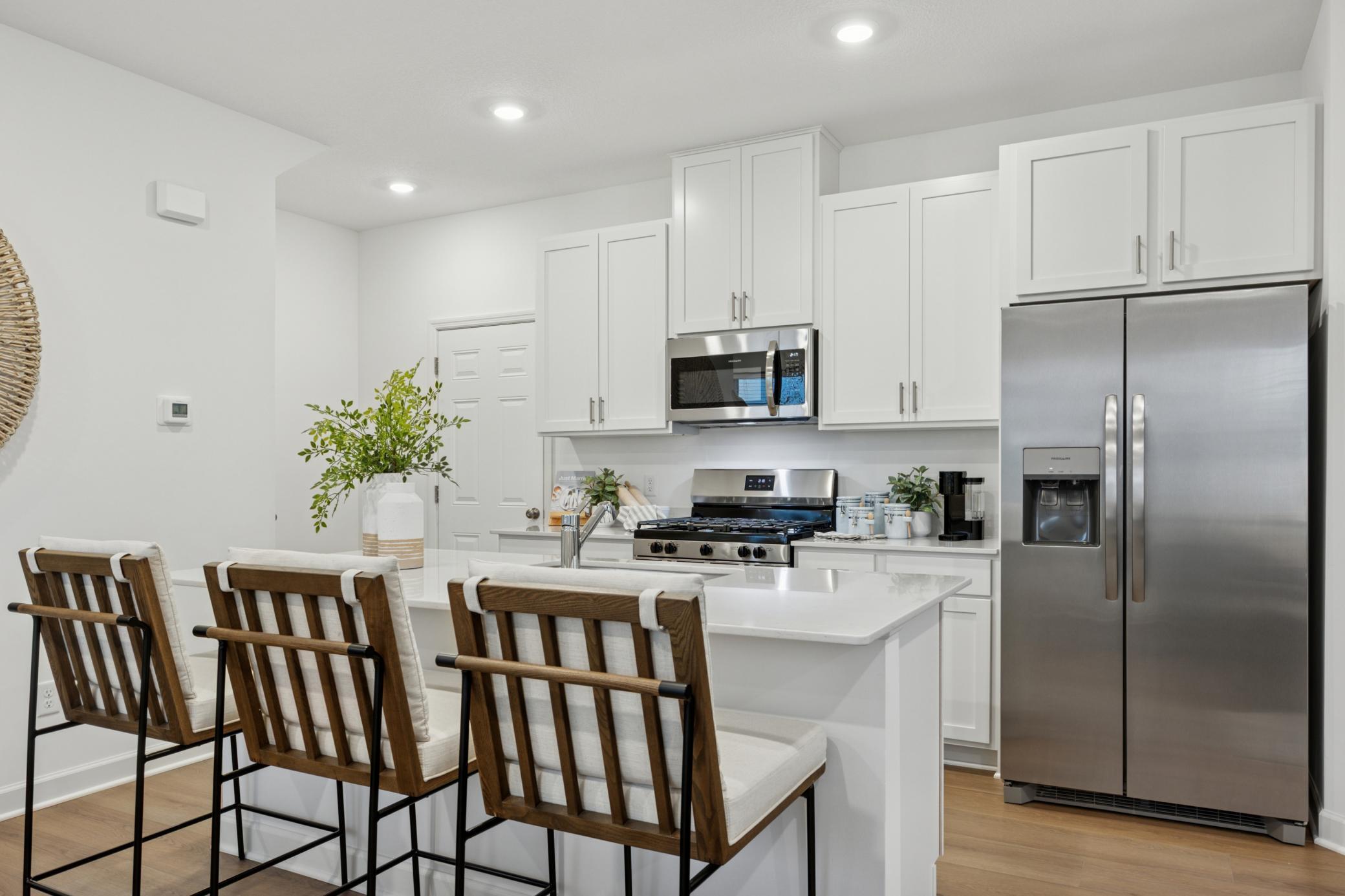 (Photo is of a model home, finishes will vary) A multifunctional center island pairs with abundant cabinetry and all-new stainless steel appliances to create a sleek design in this breezy kitchen—perfect for cooking meals of all sizes.