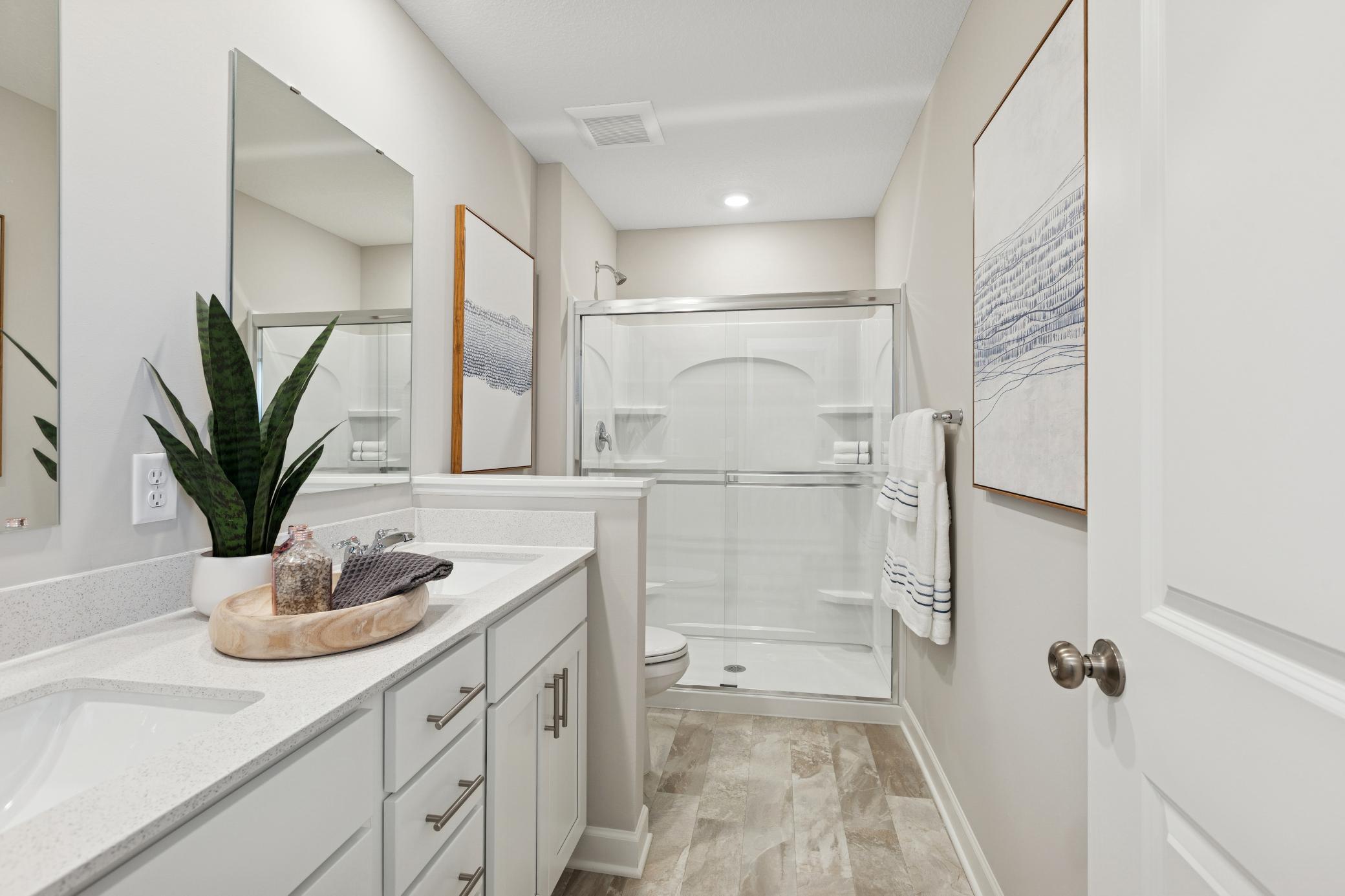 (Photo is of a model home, finishes will vary) A dual-sink vanity with separate plate glass mirrors and a glass-enclosed shower promote timely routines