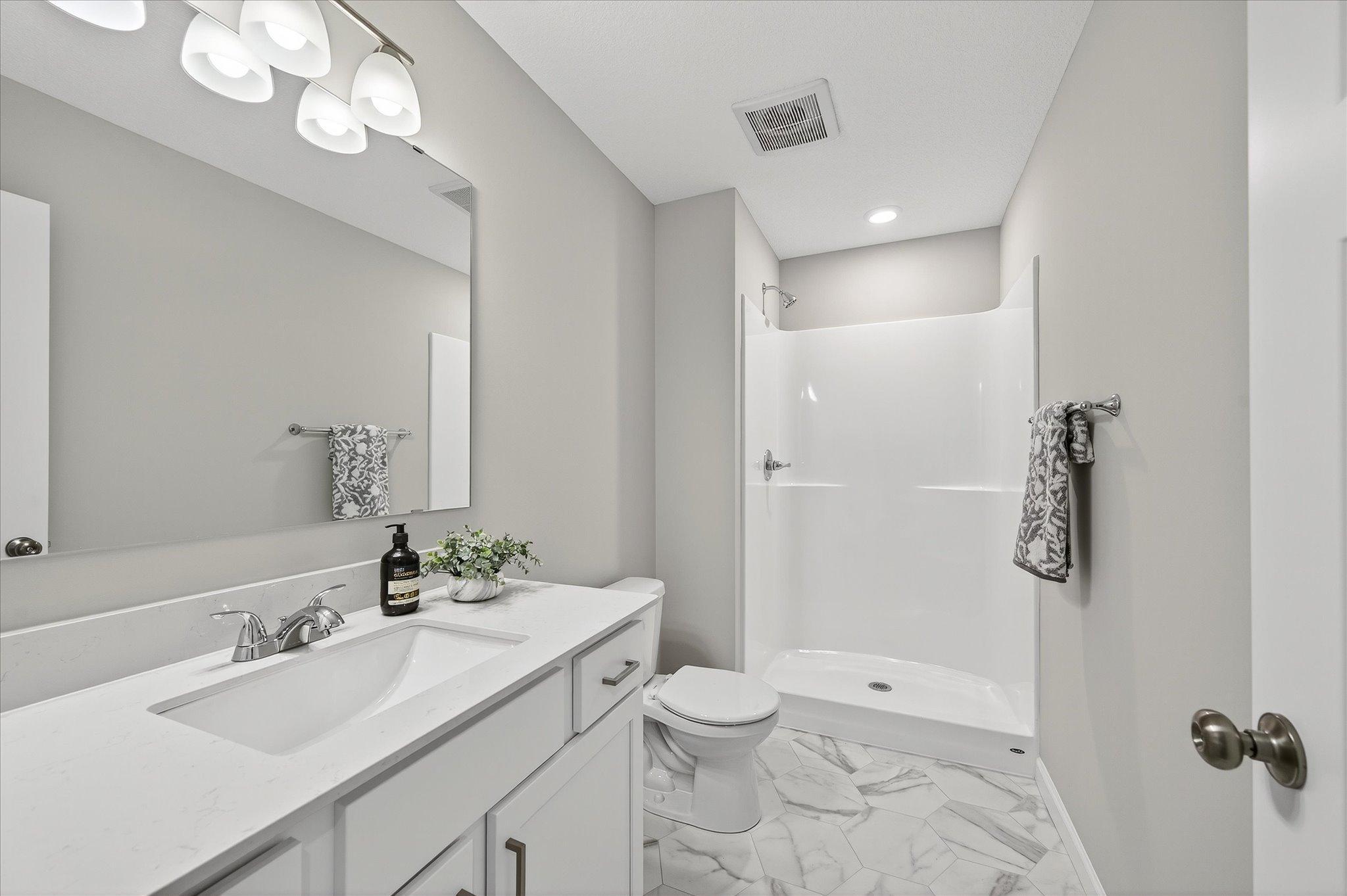 A conveniently located lower-level bathroom makes the finished basement feel like a complete living space of its own. *photos of a previously staged home, not all options & finishes may be exact.*