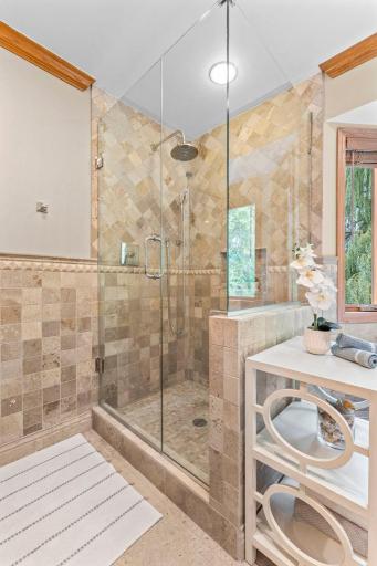 Walk-in shower with travertine tiling and glass enclosure
