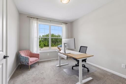 Just beyond the welcoming foyer, a sunlit office framed by a large picture window provides an ideal space for work or study