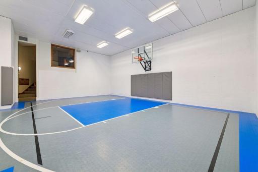 The expansive lower-level sport court includes a basketball hoop and ample room for multiple activities, making it a standout space for recreation and play.