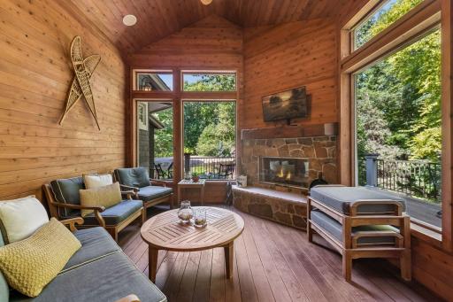 The three-season porch is anchored by a wood-burning fireplace and offers generous seating, creating a warm, versatile retreat.