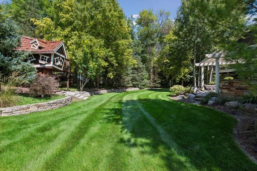 Large backyard with thoughtful landscaping and a beautiful line of mature trees for added privacy.