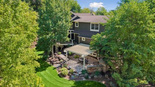 View of the backyard and back patio surrounded by beautiful mature trees.