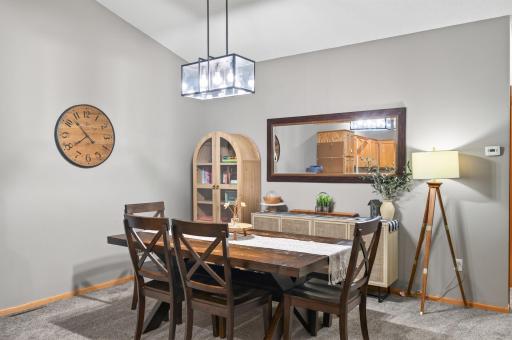 The spacious dining area features an updated light fixture for modernized living, flowing effortlessly into the open kitchen and living room.