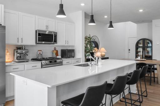 The large center island gives everyone a place to gather, while the bright cabinetry, modern lighting, and beautifully maintained finishes still feel almost brand new