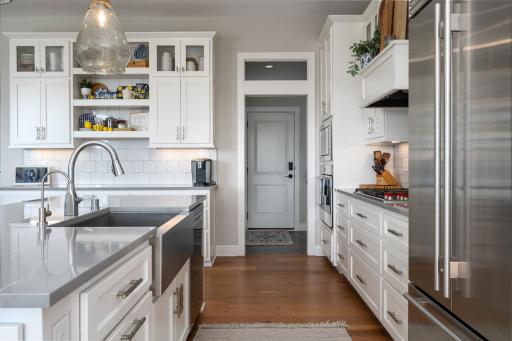 Apron-front stainless steel sink in large center island. Walkway to large 6x9 pantry with ample storage, a mini-frig, and an undermount sink.