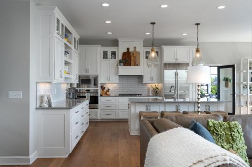 Custom cabinetry, hardware, lighting, and Shaw flooring give this inviting kitchen a warm coastal feel.