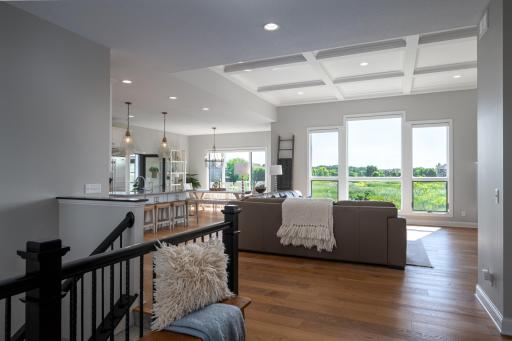 Your great room welcomes you with walls of SE views, remote-controlled blinds, a coffered ceiling, a stacked stone fireplace, and Shaw flooring, providing exceptional quality and easy everyday living.