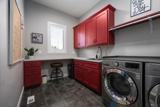 Main-level laundry room features a folding table, stainless sink & cabinets.
