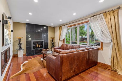 Main level family room features surround sound speakers, wood burning fireplace with views of the backyard.