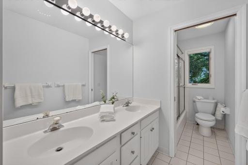 Full bath in hallway upstairs features double sinks and separated bath/toilet area.