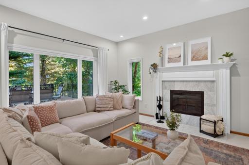 Large windows allow natural light to pour in and the fireplace creates a cozy central focus for this gathering space.