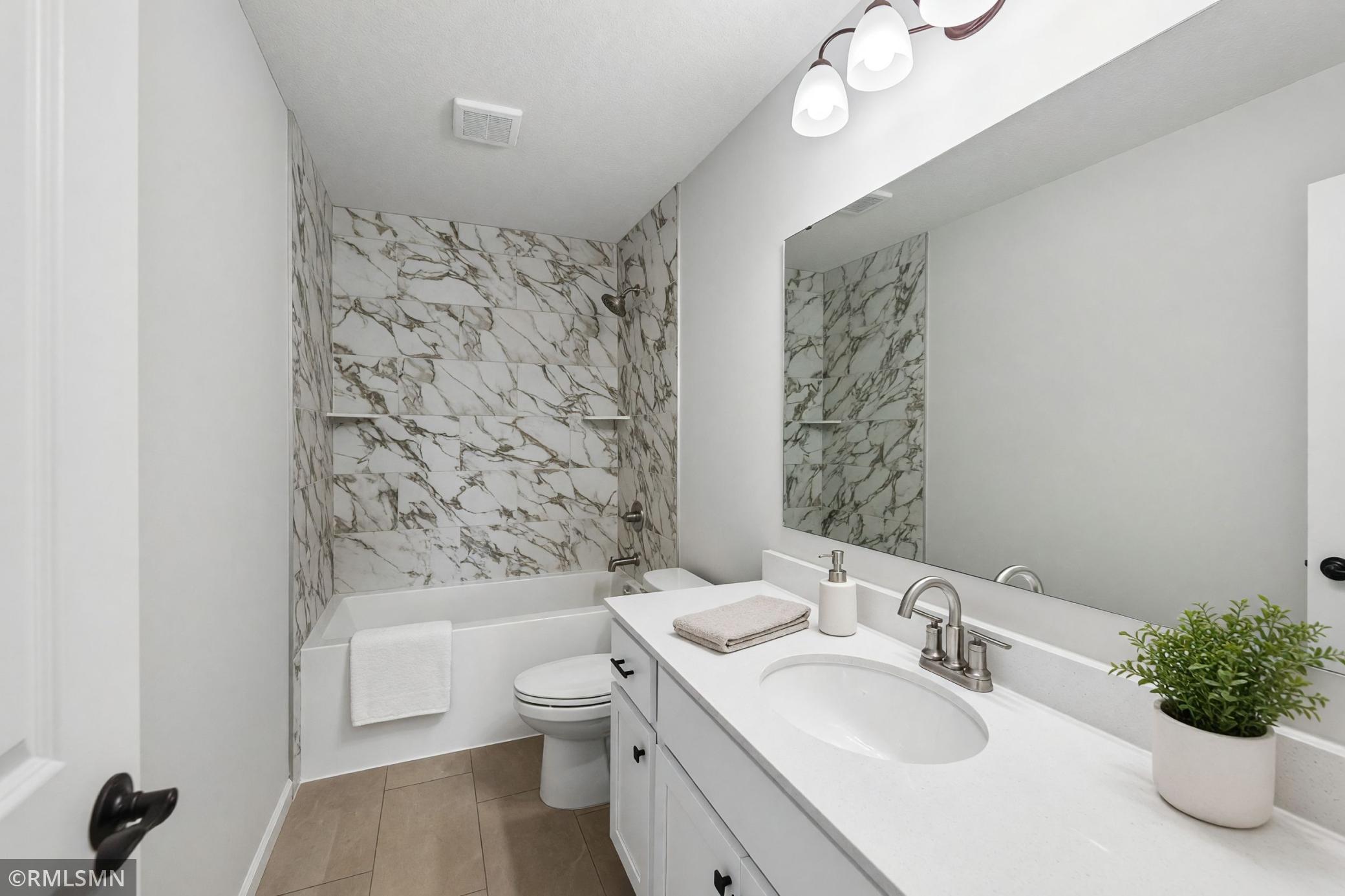 Full bath featuring a bright vanity and tiled tub/shower surround