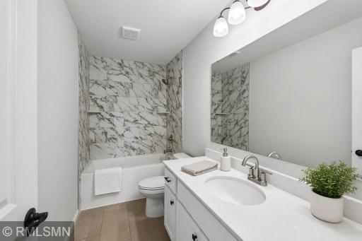 Full bath featuring a bright vanity and tiled tub/shower surround