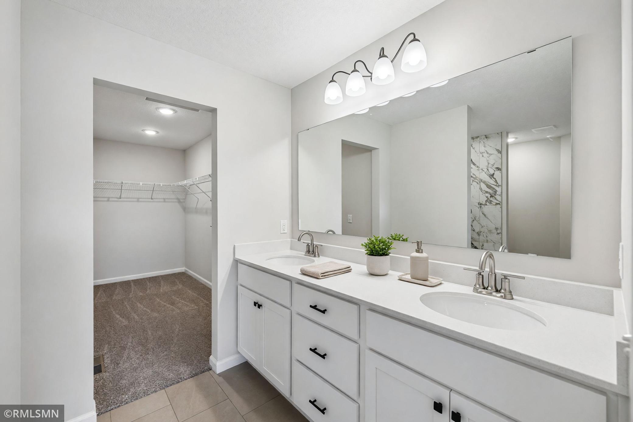 Spacious primary bath with dual-sink vanity, tiled shower and walk-in closet