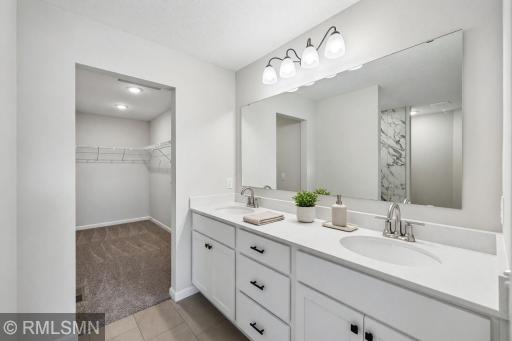 Spacious primary bath with dual-sink vanity, tiled shower and walk-in closet