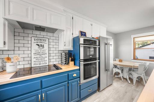 Renovated Kitchen includes stainless steel refrigerator, microwave, and oven along with a sleek glass cooktop.