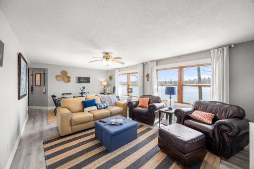 Open concept dining room and living room with large windows overlooking the water