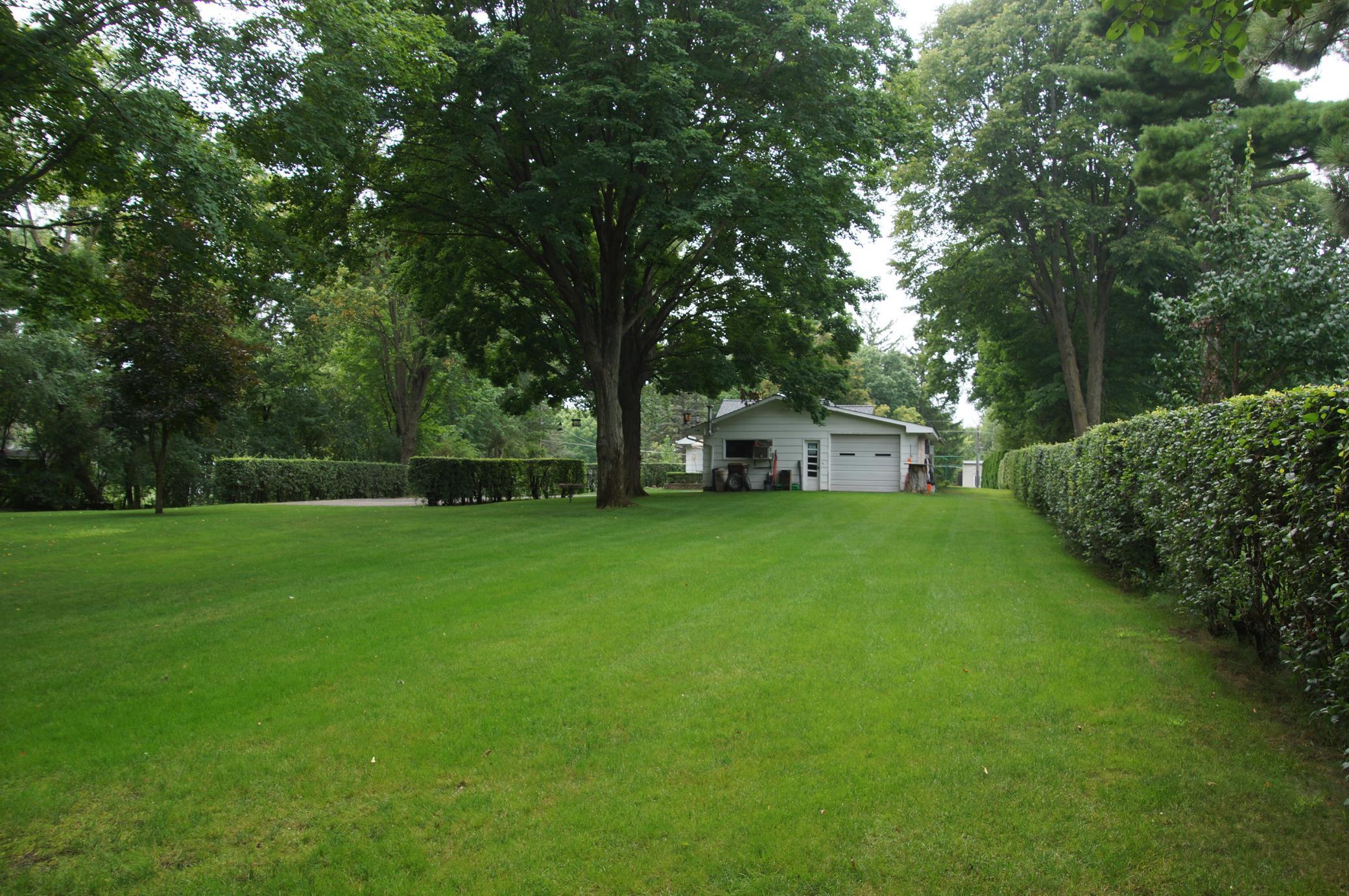 Standing at the north east corner by the firepit looking to the west. Hedge on the right marks the property line. There is more area to the left of the hedge by the driveway.