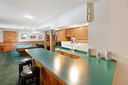 Lower-level rec room with wood paneling and pool table