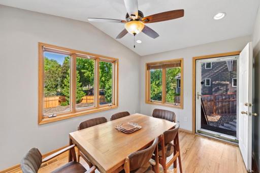 Dining area with ceiling fan and wooded backyard views