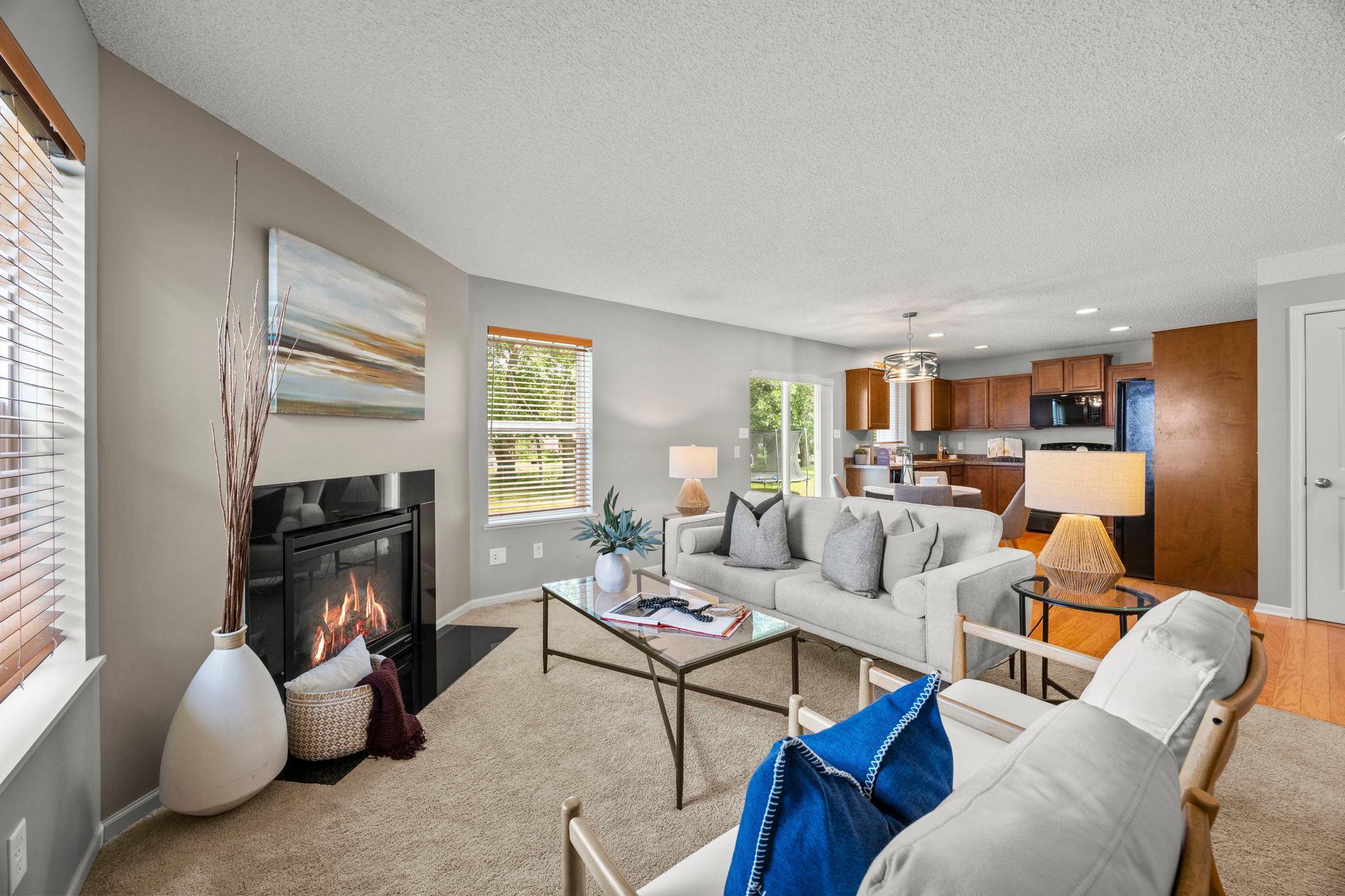 The living room feels comfortable and relaxed, featuring soft carpeting, a Heat-n-Glo fireplace, and large windows that bring in natural light and views of the backyard.