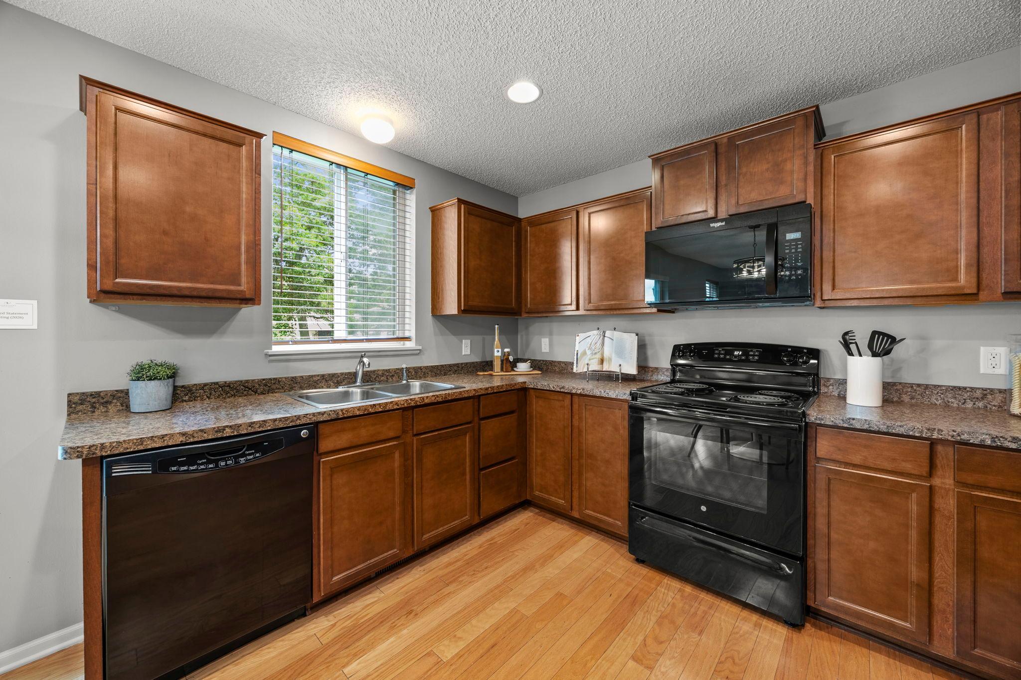 The kitchen is both functional and stylish, with hardwood floors and granite countertops.