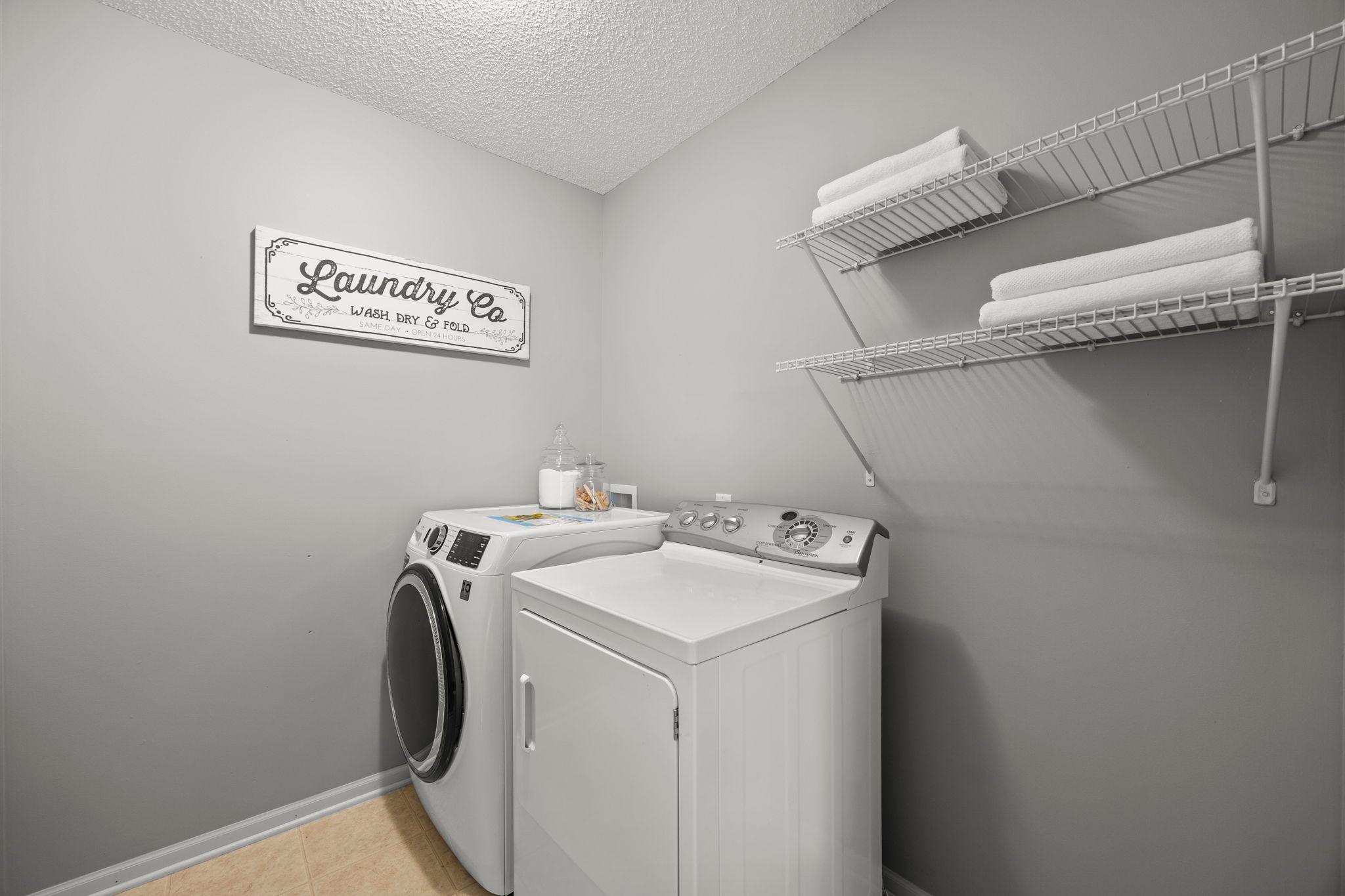Upper-level laundry room, featuring a GE smart washer (2023), dryer, and built-in shelving, enhances daily routines.