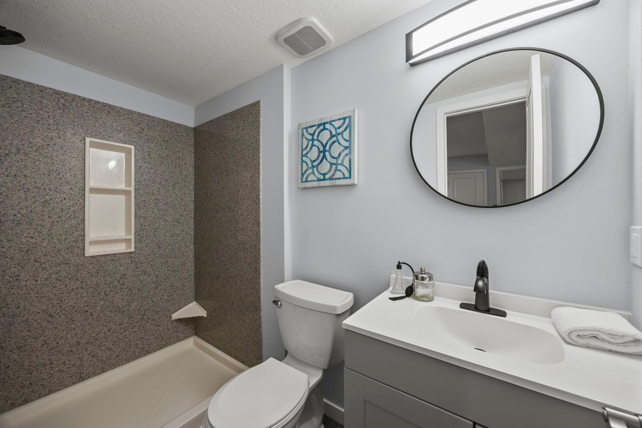 Nearby lower-level bathroom with walk-in shower. Additional storage is thoughtfully tucked into a finished under-stair closet.