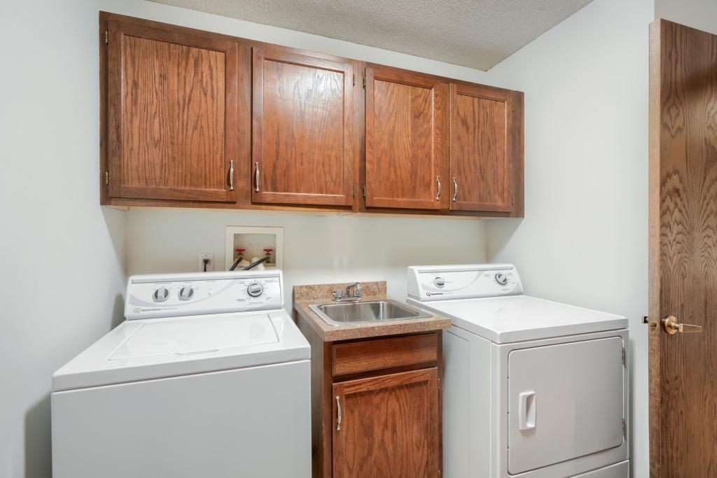 In unit laundry room with lots of extra storage cabinets.