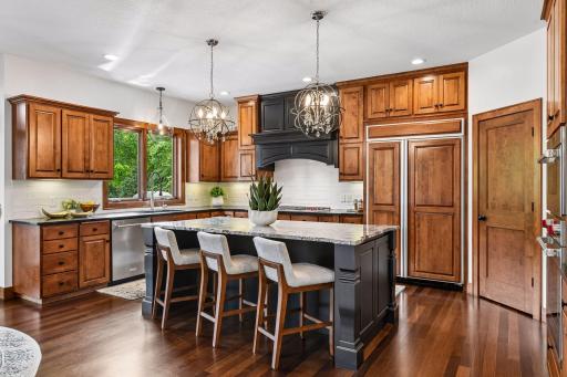 Crafted for discerning buyers, this stunning chef's kitchen showcases custom cabinetry, rich hardwood floors, designer lighting, and an oversized granite island. A timeless blend of elegance, function, and everyday luxury.