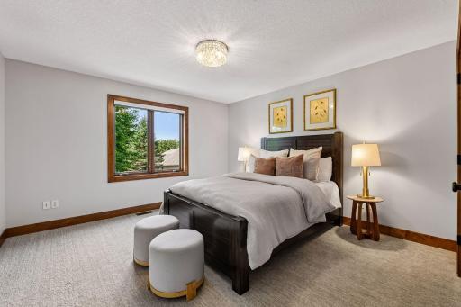 Spacious and well-appointed secondary bedroom suite featuring generous proportions, plush carpeting, and large windows that fill the space w/natural light. Thoughtfully designed for comfort and privacy, offering an inviting retreat w/bathroom ensuite