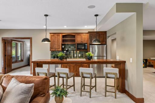 Designed for exceptional entertaining, the lower-level bar area features custom cabinetry, serving space for guests, and seamless connection to the family room. A sophisticated destination for game days, cocktail hours, and memorable gatherings.