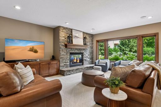 Escape to the beautifully finished walkout lower level, where a striking floor-to-ceiling stone fireplace, custom built-ins, and expansive windows create a warm yet sophisticated gathering space. Perfect for entertaining, relaxing, and enjoying.
