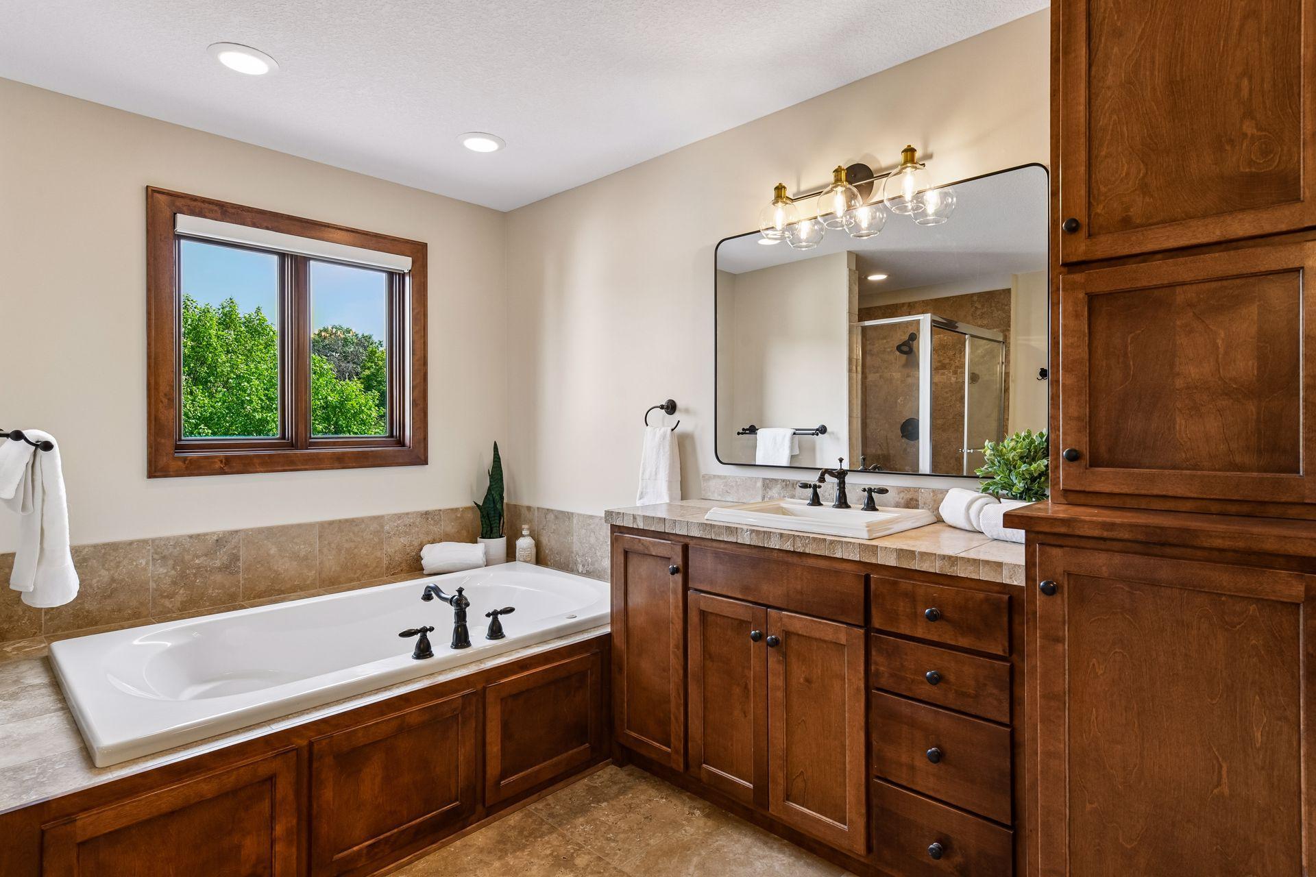 Indulge in a spa-inspired primary suite bath featuring a luxurious soaking tub, walk-in tiled shower, dual vanities, and rich custom cabinetry. Thoughtfully designed, upscale finishes and serene views. Private retreat offers everyday resort living.
